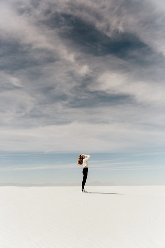 Femme sur du sable blanc, la mer est bleue, le ciel est voilé - Le blues de l'hiver - Sandrine Rey professeur de yoga Aix en Provence
