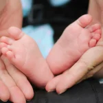 Pieds de bébé tenus dans des mains d’adulte symbolisant la douceur et le bien-être à Aix-en-Provence
