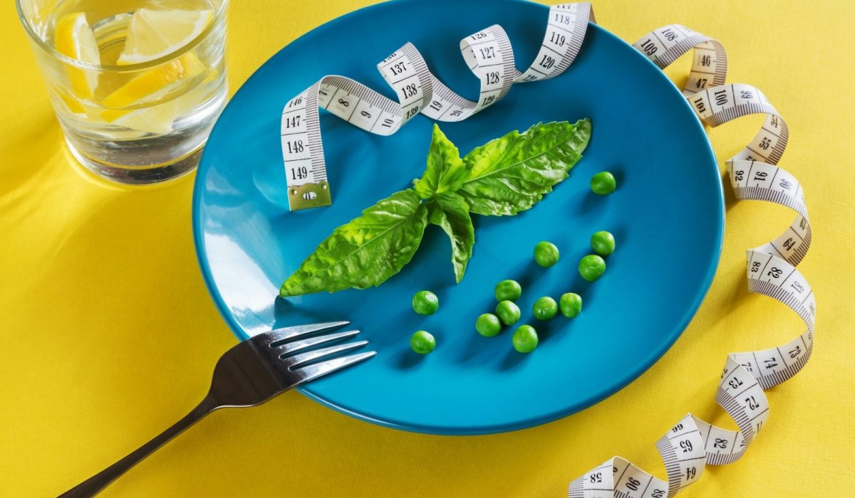 Perdre du poids avec la Naturopathie - Assiette bleu avec des petits pois et un centimètre sur une table jaune